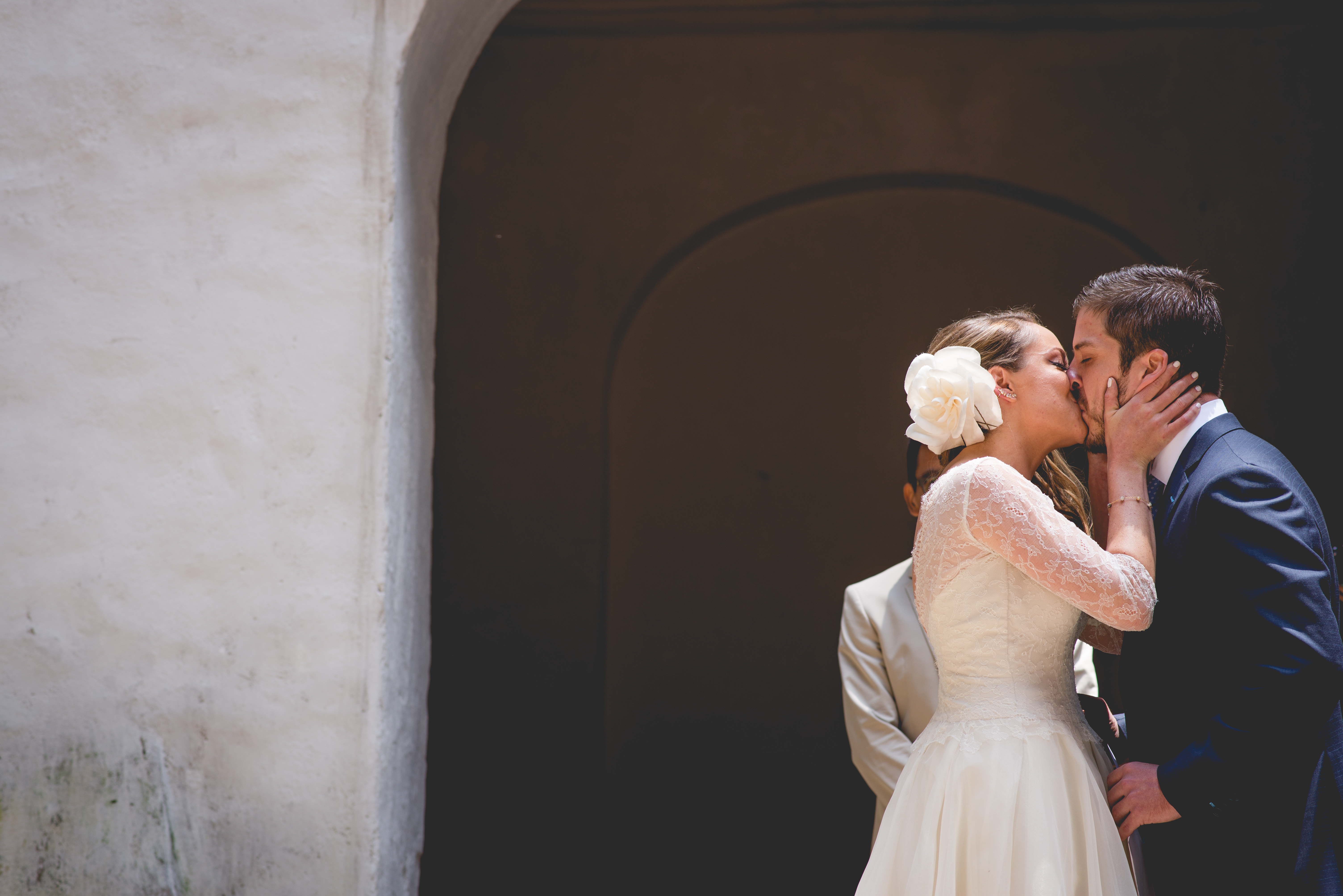Bride and groom kissing beneath an arch, complete wedding photograph